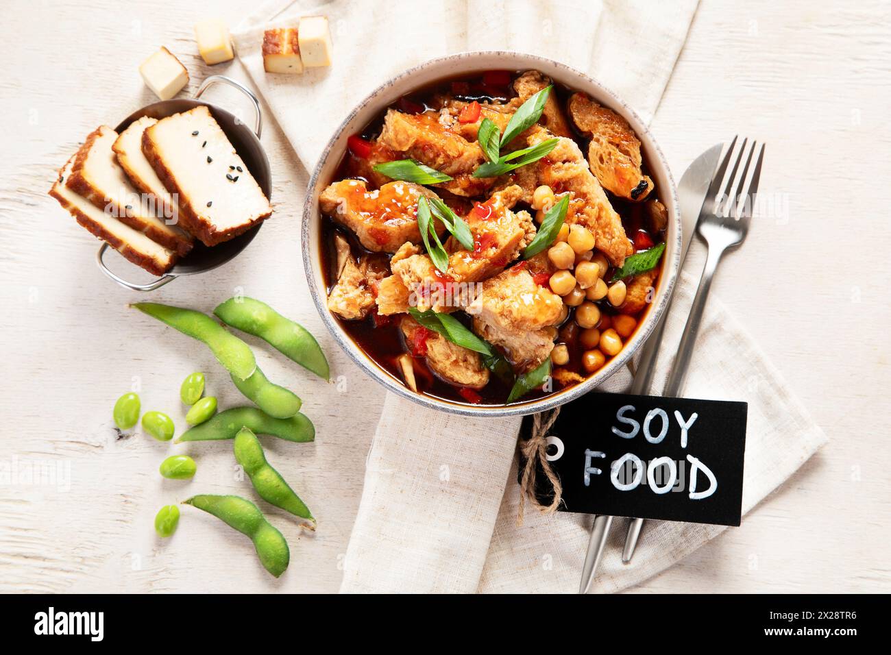 Soia con carne di soia, cipolla e tofu su sfondo di legno chiaro. Cibo vegano. Vista dall'alto Foto Stock