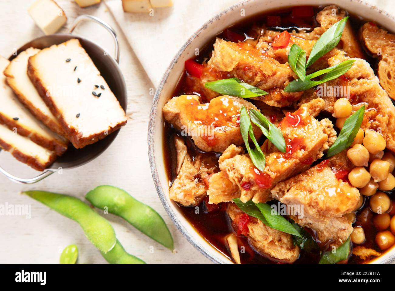 Soia con carne di soia, cipolla e tofu su sfondo di legno chiaro. Cibo vegano. Vista dall'alto Foto Stock