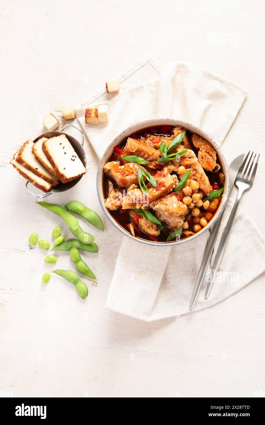 Soia con carne di soia, cipolla e tofu su sfondo di legno chiaro. Cibo vegano. Vista dall'alto, copia spazio Foto Stock