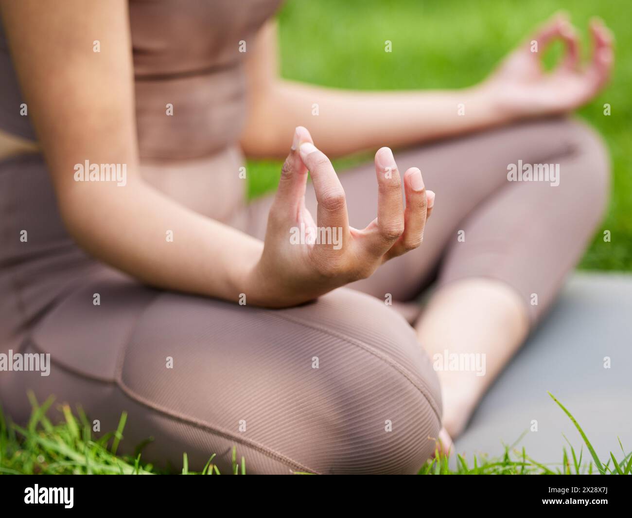 Donna, mani e meditazione con yoga in giardino per la consapevolezza, zen olistico ed equilibrio sul prato. Yogi naturali, persona e relax per pilates con Foto Stock