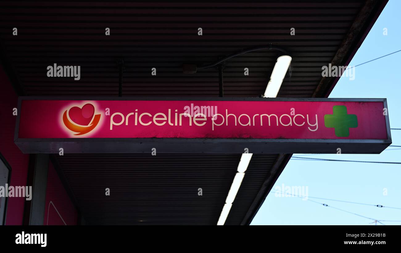 Cartellone della Priceline Pharmacy illuminato prevalentemente di rosa, fuori da uno dei loro negozi di farmacia durante il giorno Foto Stock