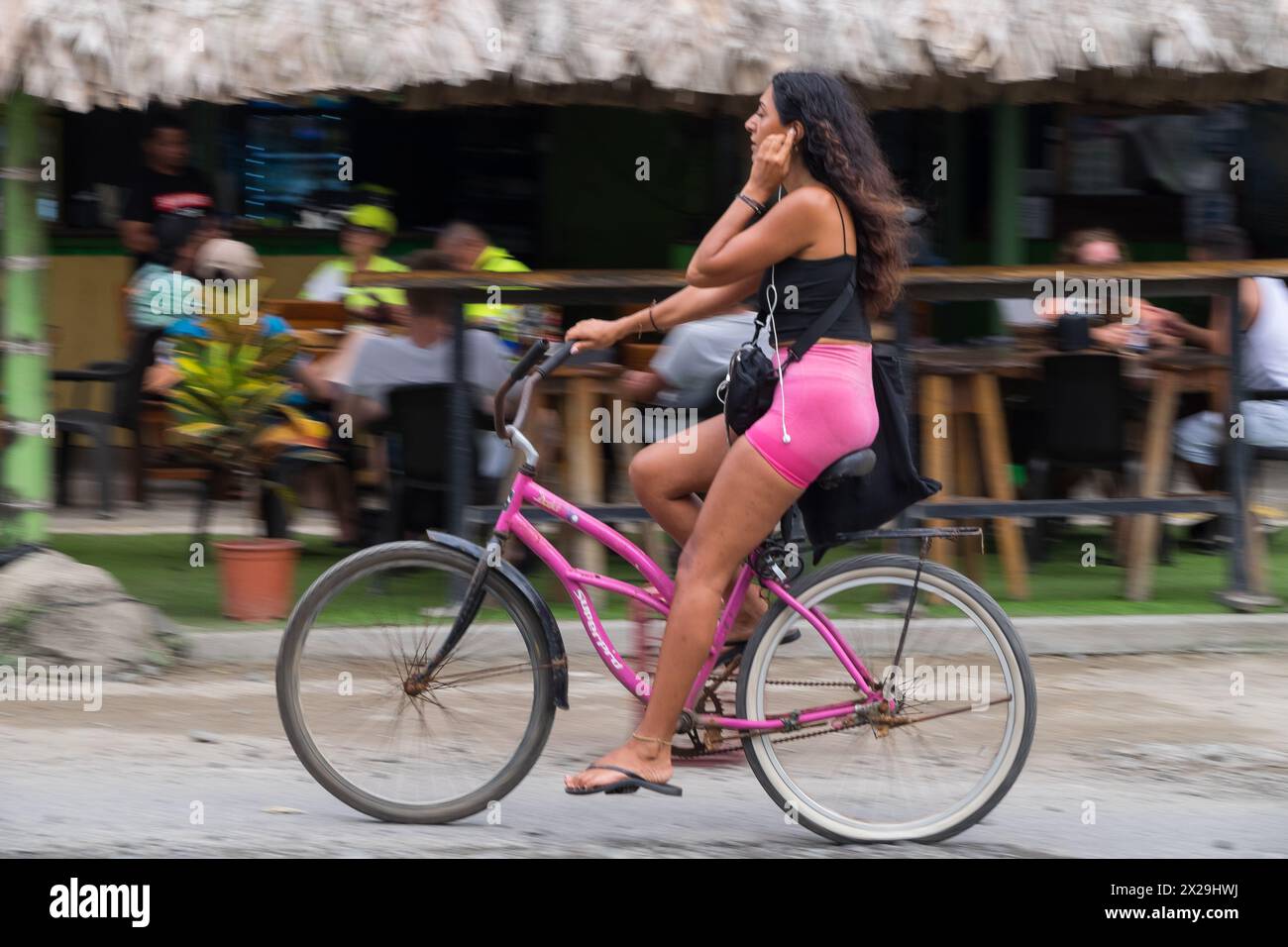 Giovane donna in bicicletta per le strade di Puerto Viejo de Talamanca in Costa Rica Foto Stock