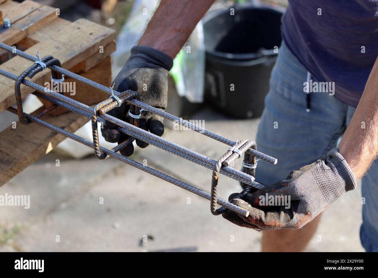 Il costruttore professionista lavora con l'acciaio di rinforzo. Lavori di costruzione in corso. Uomo con guanti grigi con struttura metallica. Foto Stock