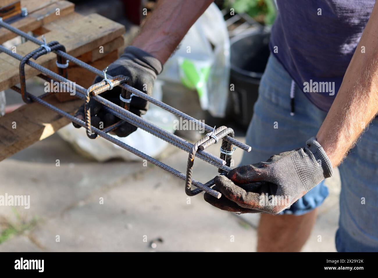 Il costruttore professionista lavora con l'acciaio di rinforzo. Lavori di costruzione in corso. Uomo con guanti grigi con struttura metallica. Foto Stock