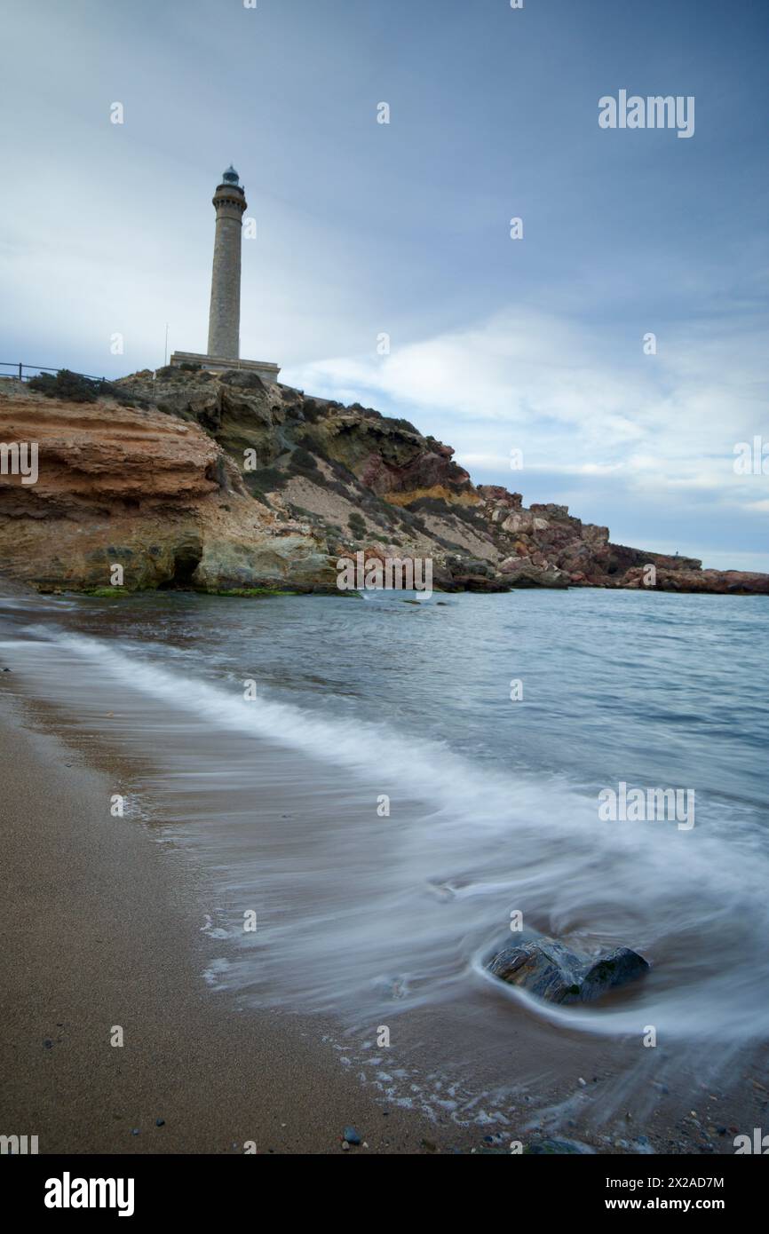 Lunga esposizione sul mare del faro e della spiaggia di Cabo de Palos, Cartagena, regione di Murcia, Spagna, con le onde che si lavano sulla sabbia. Foto Stock