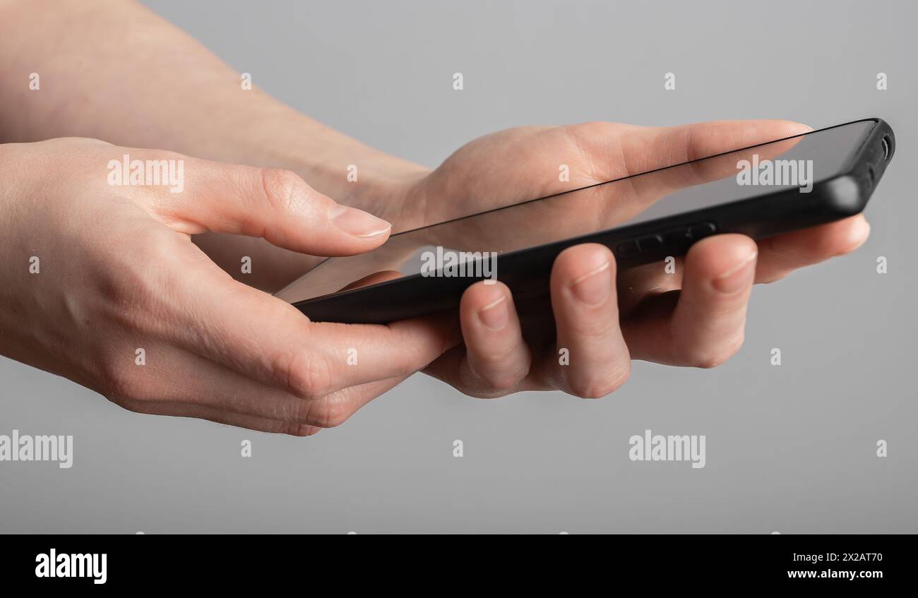 Mani che usano il telefono cellulare, scrivono messaggi, leggono notizie, social media, navigano su Internet. Foto Stock
