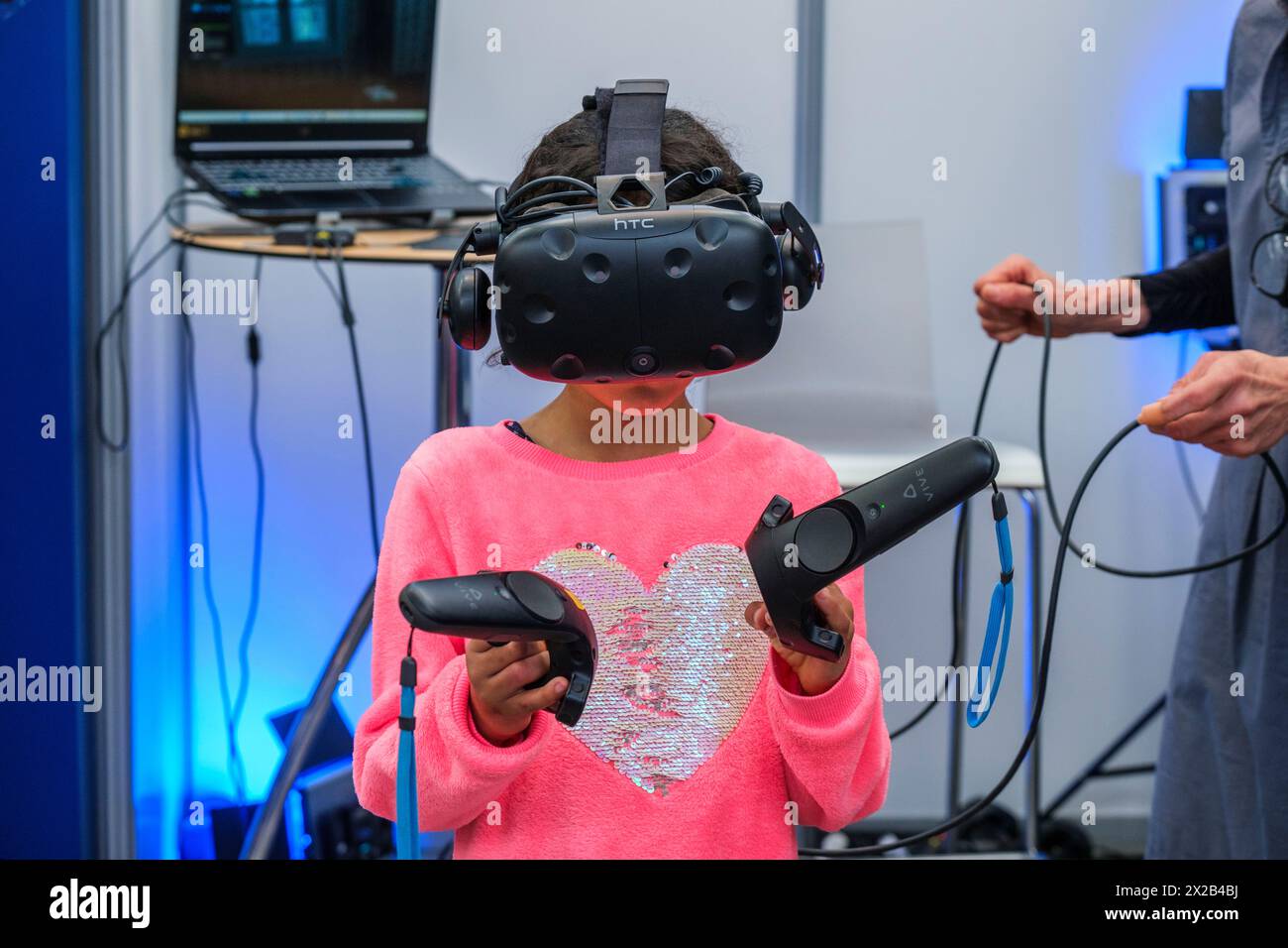 Bambino immerso in un gioco di realtà virtuale che indossa un casco speciale e una mano in movimento con i joystick | un enfant est immergé dans un jeu en realité virute Foto Stock