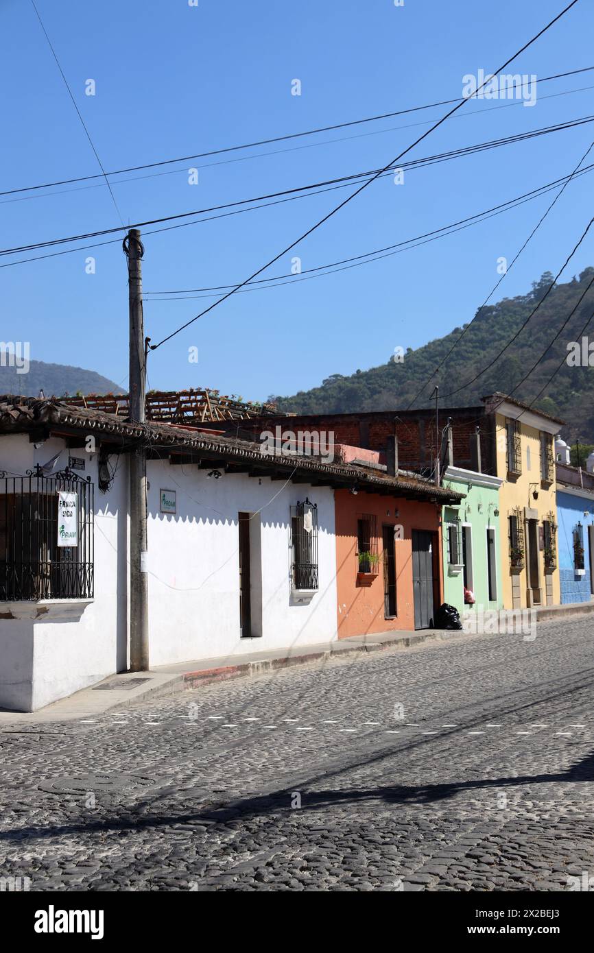 Antigua, l'antica capitale del Guatemala. Tranquilla scena di strada, uno di una serie. Edifici colorati dell'America centrale. Niente persone. Cavi, ciottoli. Foto Stock