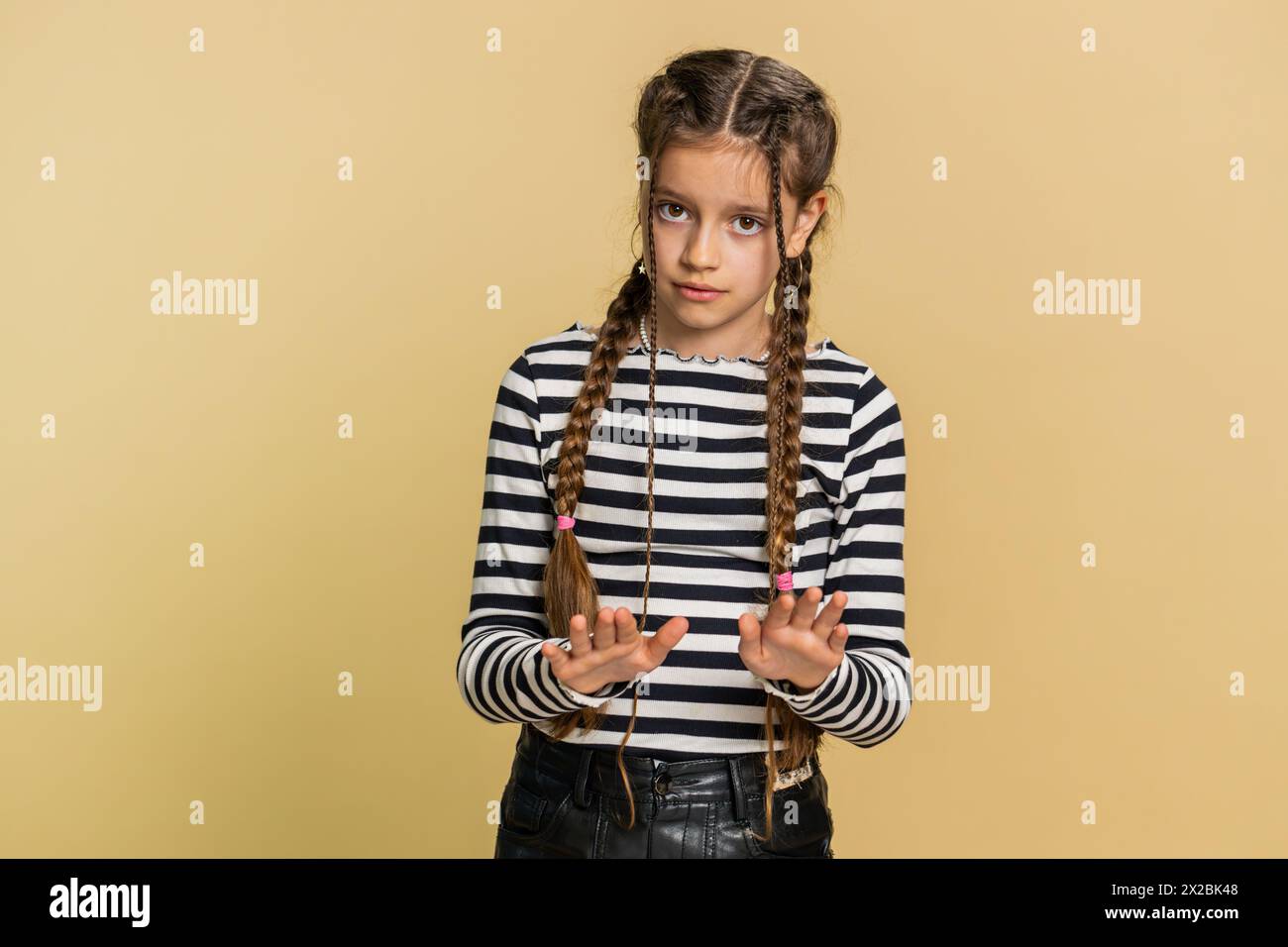 Ehi, fate attenzione. Severo bambino preadolescente ragazzo avvertimento con gesto delle mani ammonito che dice di no, fate attenzione a rimproverare e dare consigli per evitare il cartello di pericolo. Bambini adolescenti in background beige Foto Stock