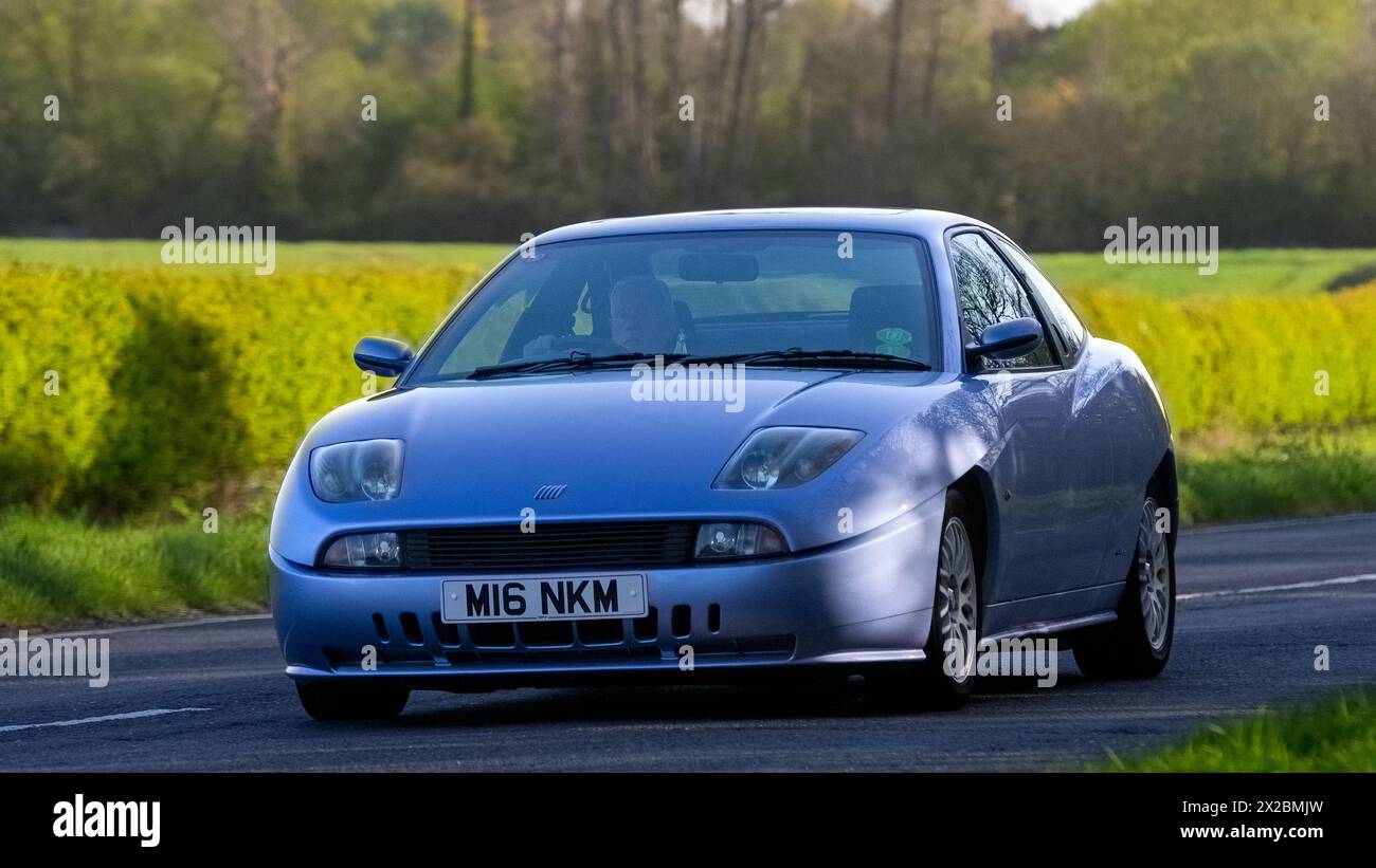 Bicester, Regno Unito - 21 aprile 2024: 1998 Fiat Coupe blu, auto d'epoca che guida su una strada britannica Foto Stock