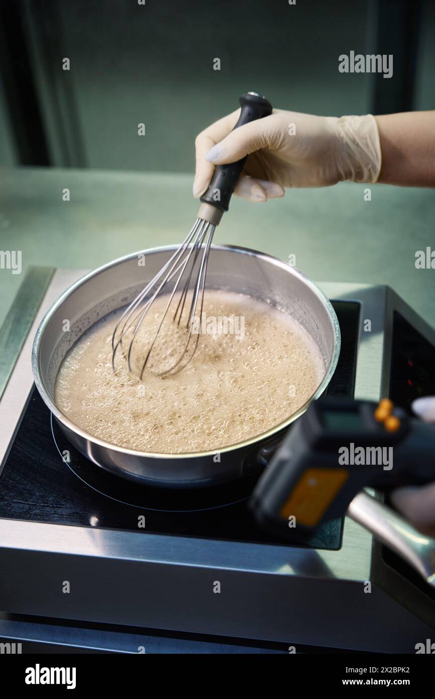 Vista ravvicinata del composto gelificante e dello zucchero in una pentola che ebollisce Foto Stock