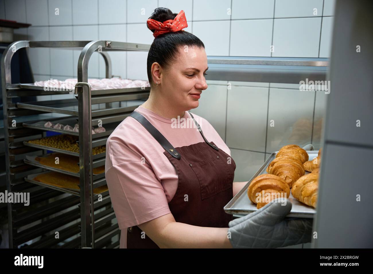 Donna sorridente che controlla la disponibilità di gustosi croissant flabby Foto Stock