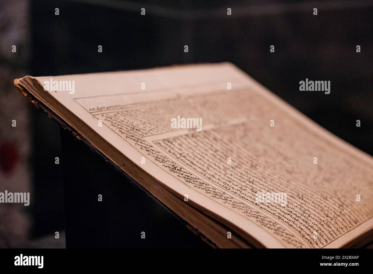 Una prospettiva illuminante che cattura una singola pagina da un Corano storico aperto, mostrando una saggezza senza tempo. Foto Stock
