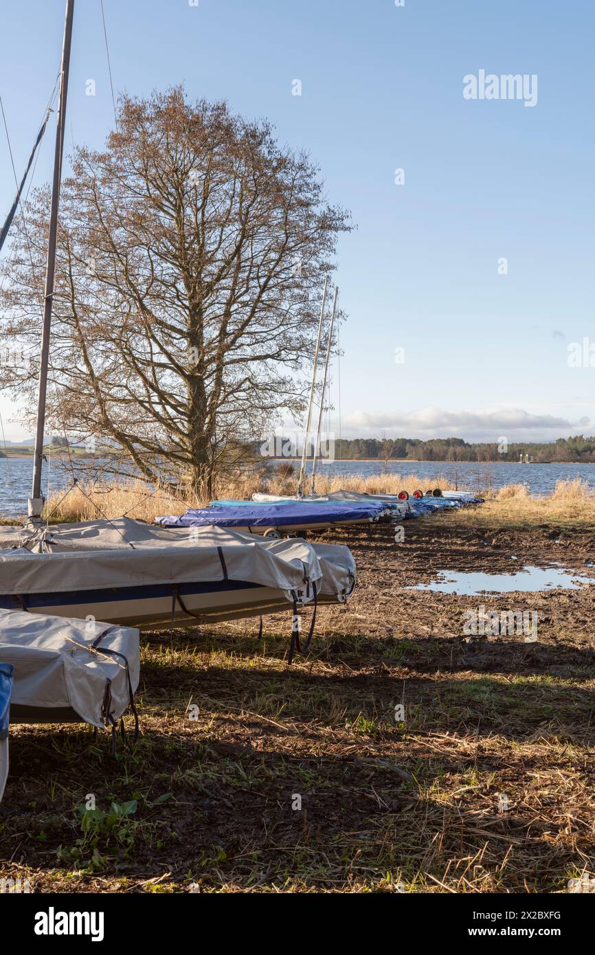 Barche a vela conservate sulla riva del lago di Skene sotto un cielo limpido all'inizio della primavera Foto Stock