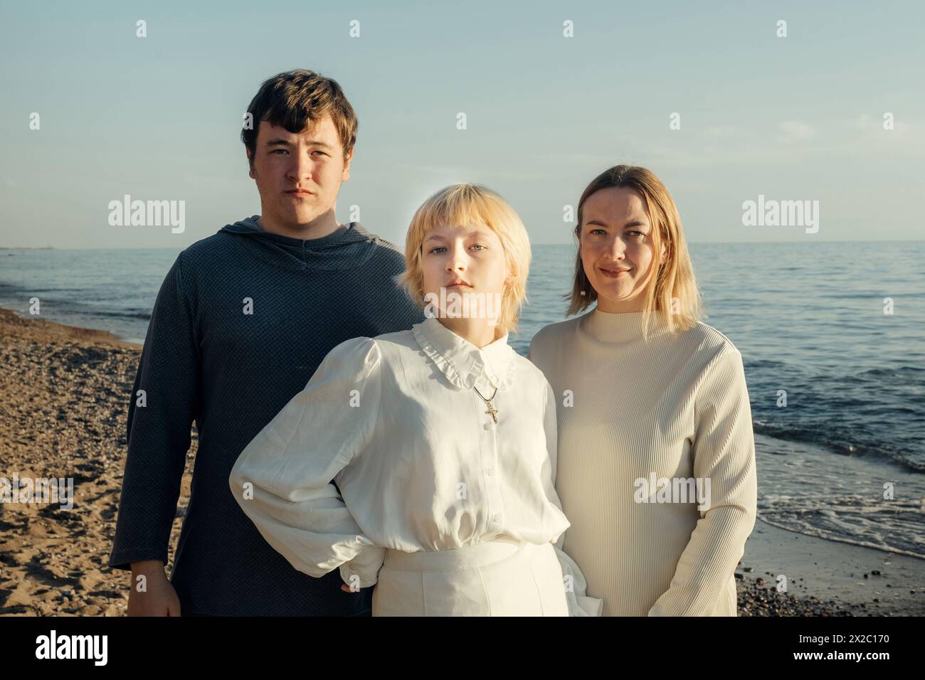 Un gruppo variegato di individui che si trovano insieme sulle rive sabbiose di una spiaggia, affacciata sull'oceano. Foto Stock