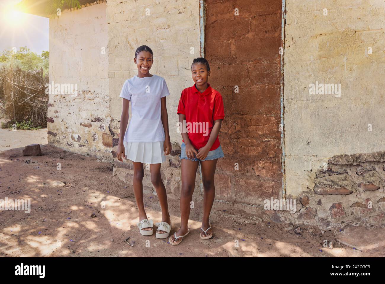 due ragazze africane sorridenti di fronte alla casa nella povera cittadina, insediamento informale Foto Stock