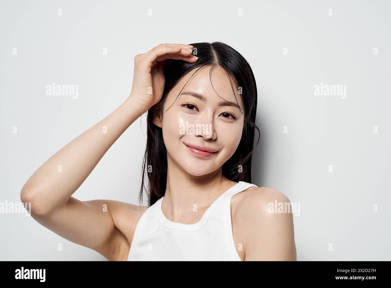 Donna asiatica che posa con la mano sulla testa su uno sfondo bianco Foto Stock