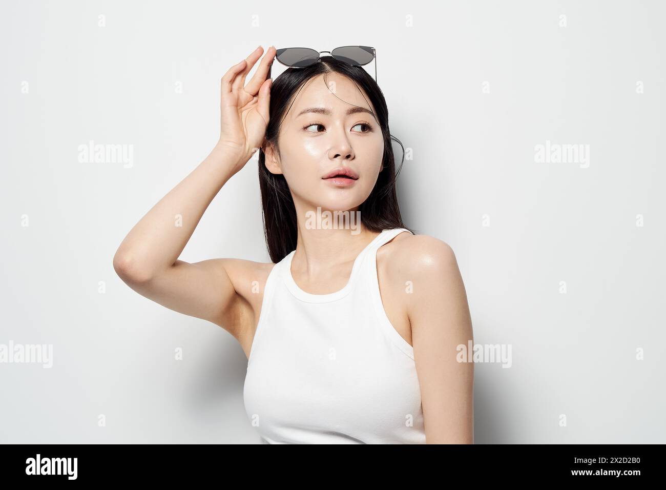 Una donna asiatica che guarda lateralmente in occhiali da sole con una mano Foto Stock