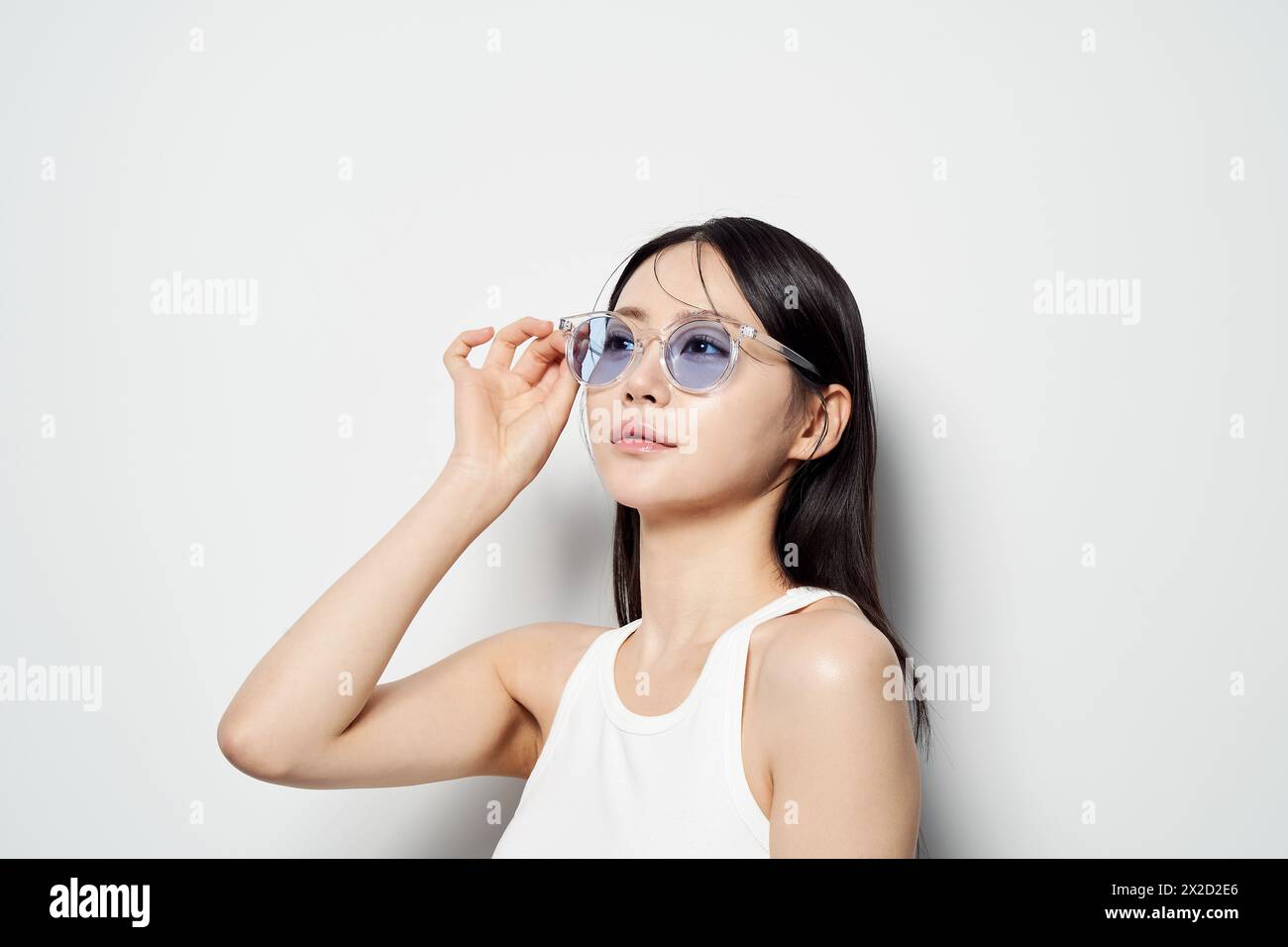 Una donna asiatica che indossa gli occhiali da sole con una mano Foto Stock