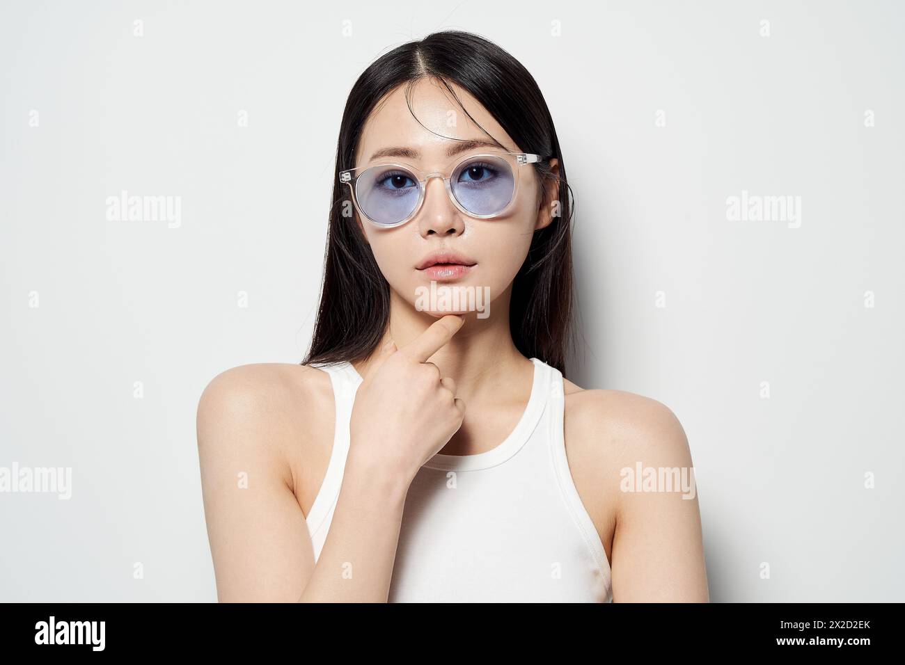 Donna asiatica che fissa dritto davanti con occhiali da sole chiari Foto Stock