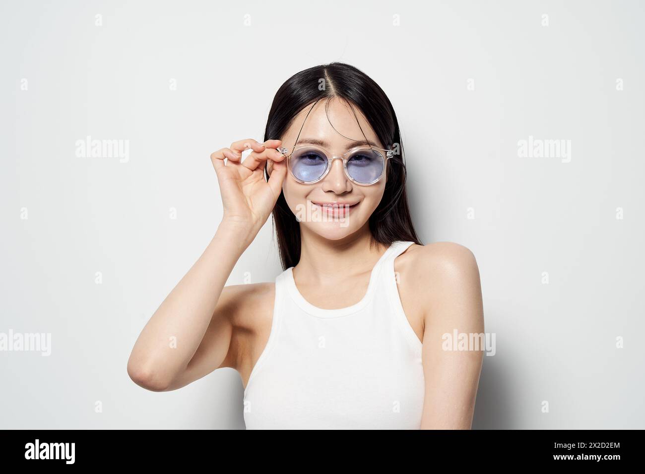 Una donna asiatica che indossa occhiali da sole e sorride Foto Stock