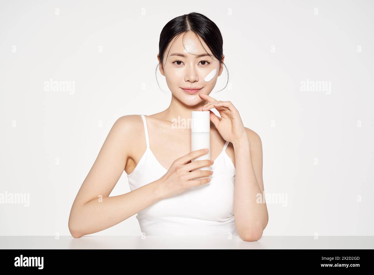 Donna asiatica posa con White Cosmetics Bottle Foto Stock