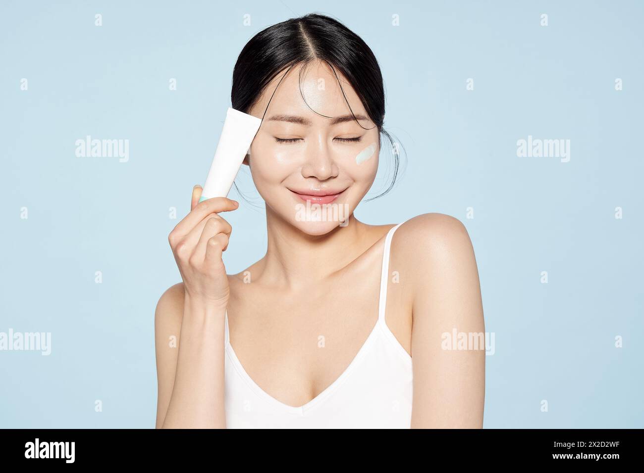 Donna asiatica posa con crema intorno ai suoi occhi Foto Stock