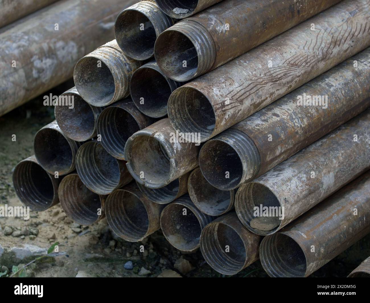 pile di tubi forati a terra. utilizzato per la foratura di tubi in metallo arrugginito Foto Stock