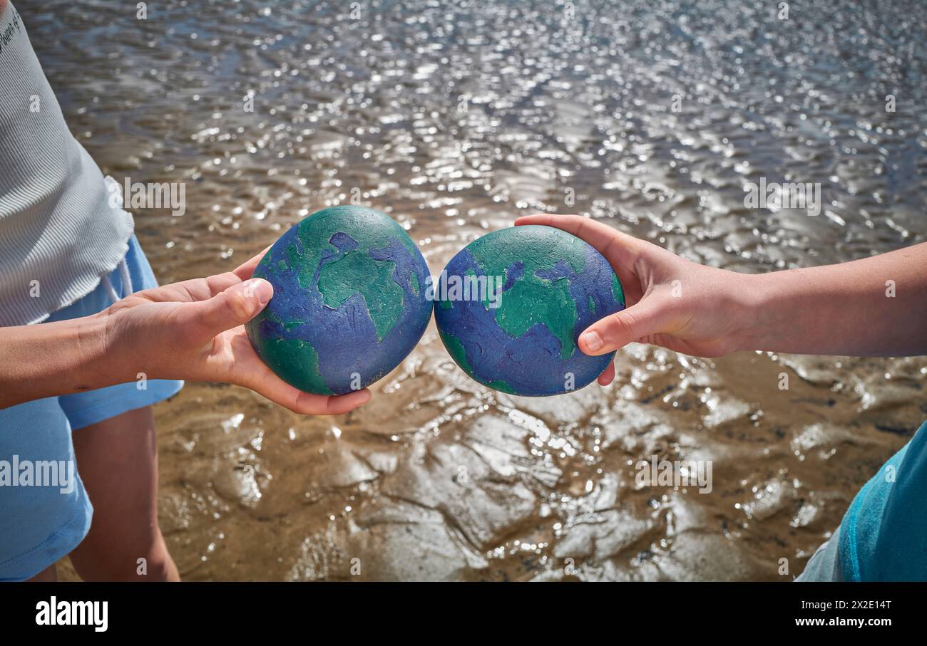 I bambini giocano sulla spiaggia di Westward ho!, Devon scambiando i ciottoli dipinti sulla terra per la giornata mondiale della Terra del 2024 Foto Stock