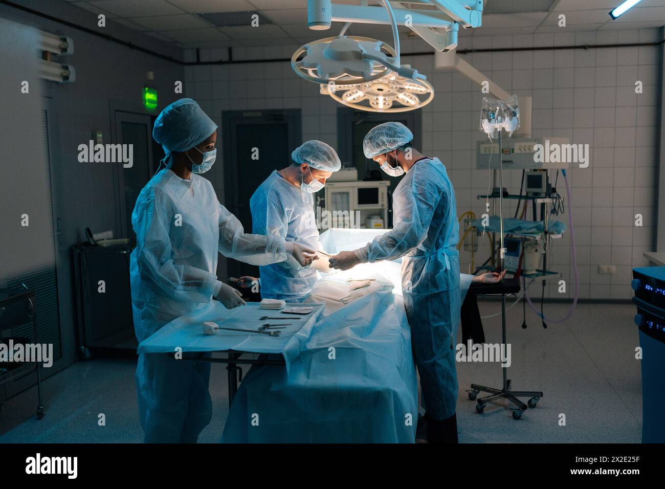 Ampia gamma di chirurghi e infermieri professionisti multietnici nell'esecuzione uniforme di interventi di trapianto di cuore sotto lampade luminose con uso medico Foto Stock