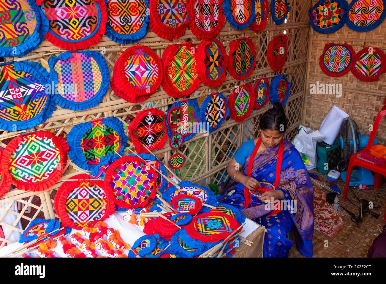 Narayanganj, Dacca, Bangladesh. 22 aprile 2024, Narayanganj, Dacca, Bangladesh: I lavoratori ricamano sapientemente ventilatori a mano con forme geometriche dai colori vivaci a Narayanganj, Bangladesh. Utilizzano bambù e filati colorati per creare ventilatori dal design complesso. Durante le estati calde, danno una brezza fresca che aiuta quando fa davvero caldo all'aperto in caso di distacco del carico. Ogni lavoratore può contare su 10 tifosi al giorno, ogni fan viene venduto per circa 1,20 USD alle fiere dei villaggi. Questa è diventata una professione tradizionale nella zona, fanno fan a mano da centinaia di anni. Credito: ZUMA Press, in Foto Stock