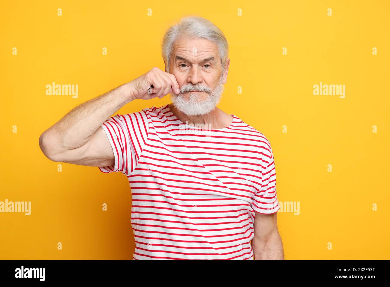 Uomo anziano che tocca i baffi su sfondo arancione Foto Stock