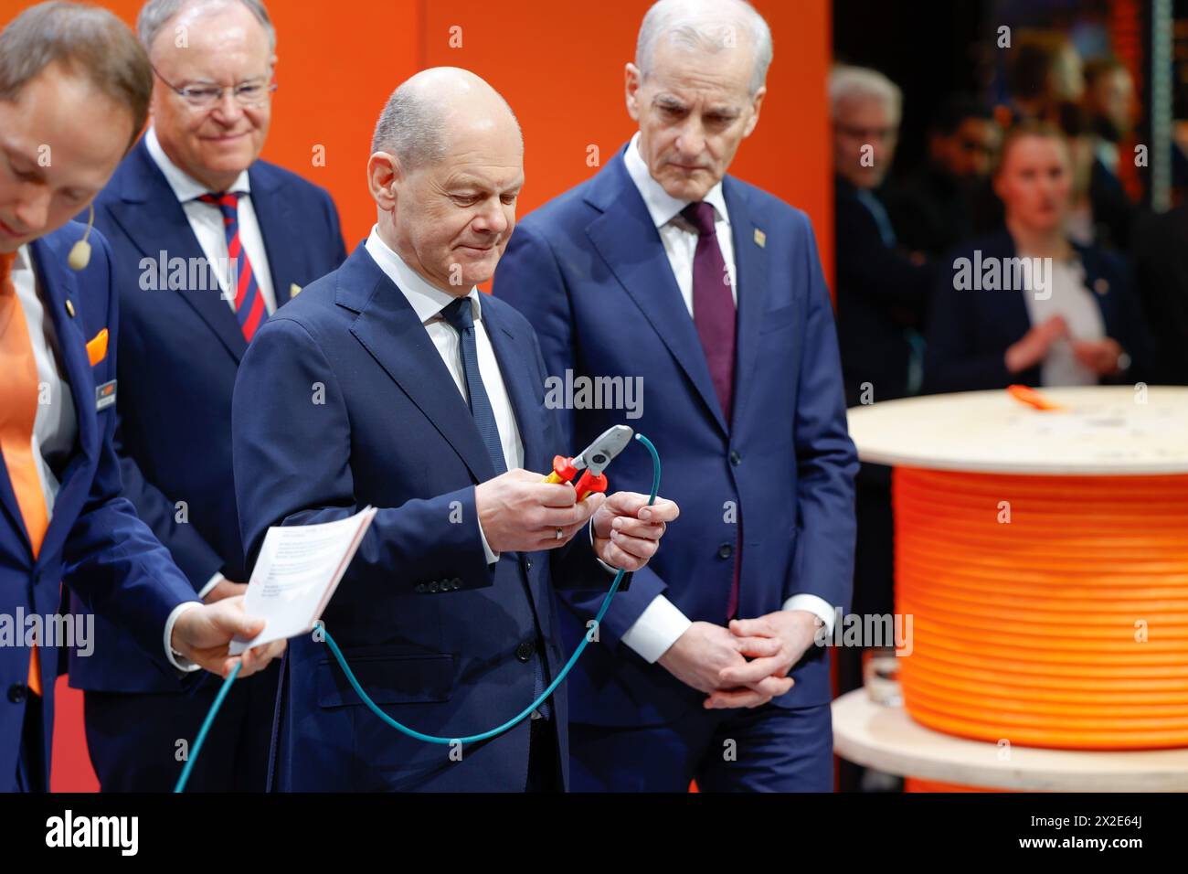 Hannover, Germania. 22 aprile 2024. Il Cancelliere tedesco Olaf Scholz (SPD) taglia un pezzo di cavo dati realizzato con un materiale di rivestimento sostenibile a base biologica per uso industriale presso lo stand Lapp. Credito: Michael Matthey/dpa/Alamy Live News Foto Stock