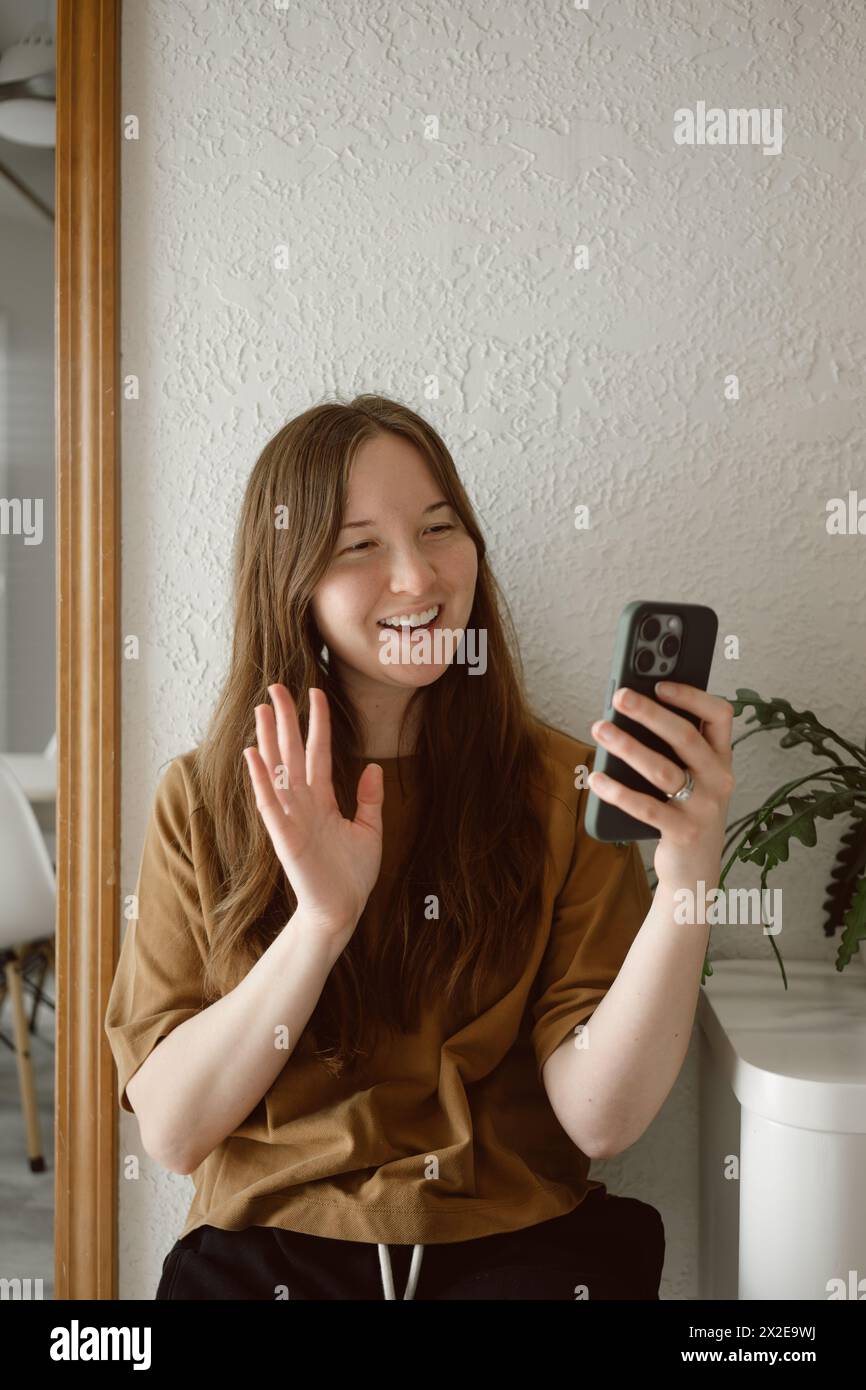 La donna saluta il telefono mentre è in videochiamata, copia spazio Foto Stock