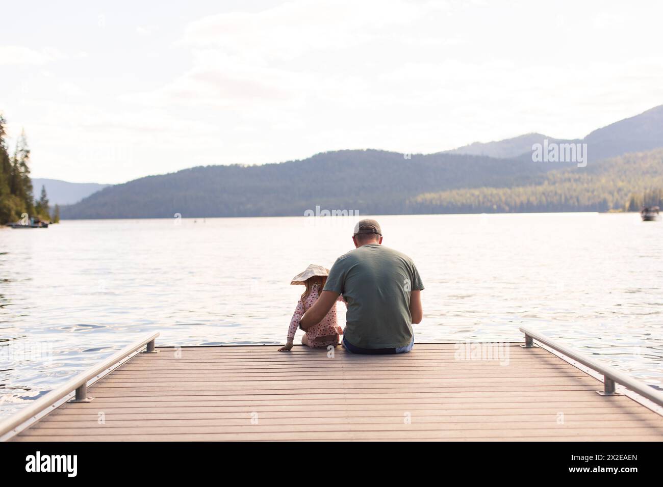 Padre e figlia seduti alla fine del molo Foto Stock