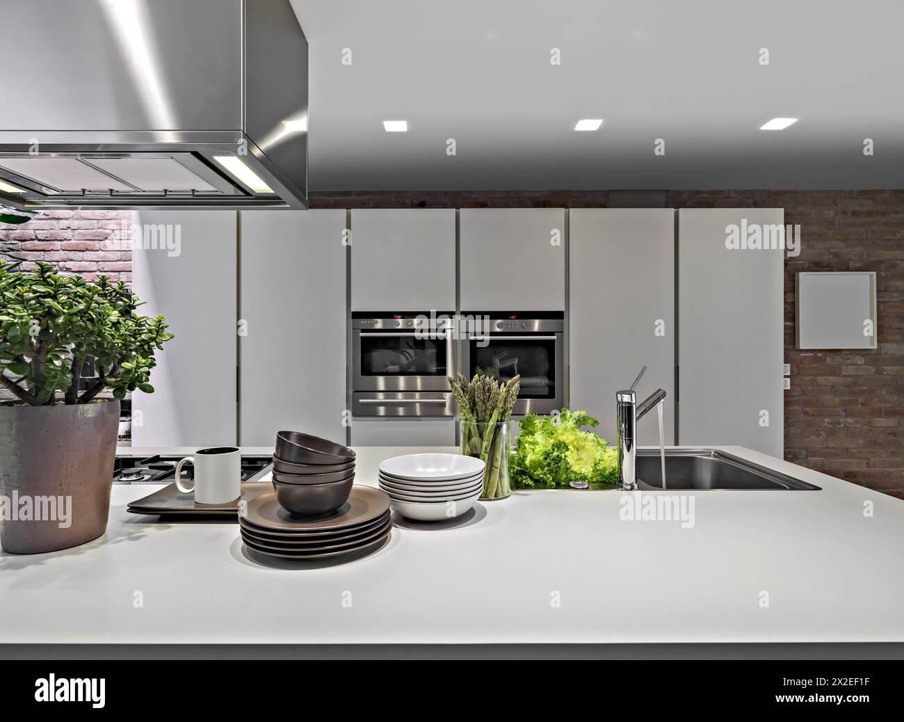 interni di una cucina moderna, in primo piano i piatti e il lavandino incorporato sullo sfondo i mobili bianchi Foto Stock