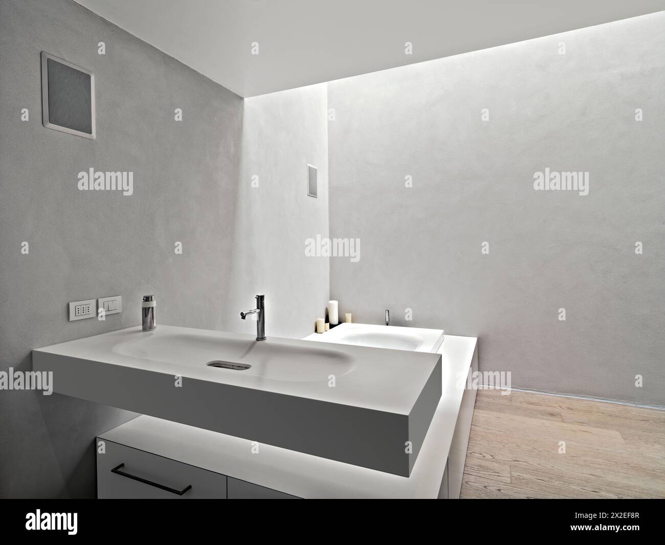 foto interne di un bagno moderno in primo piano del grande lavandino a strapiombo sullo sfondo della vasca mentre il pavimento è in legno Foto Stock