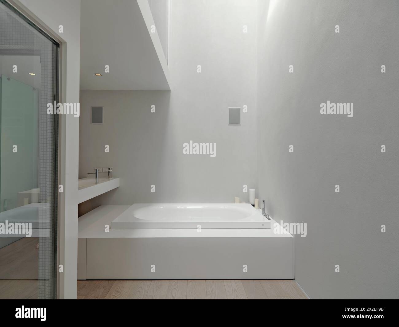 foto interne di un bagno moderno in primo piano della vasca da bagno sullo sfondo del lavabo sovrastante mentre il pavimento è in legno Foto Stock