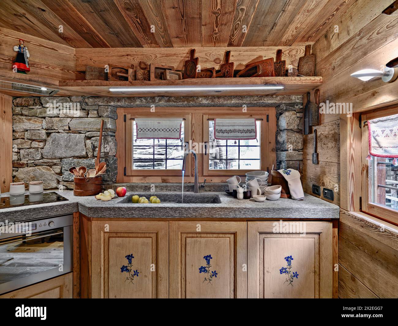 foto interna di una cucina rustica in primo piano il lavello in marmo e il rubinetto invece le pareti sono fatte di pietre Foto Stock