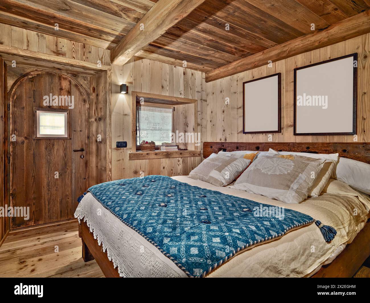 gli interni hanno girato una camera da letto rustica con soffitto in legno e pareti in legno sullo sfondo della porta in legno Foto Stock
