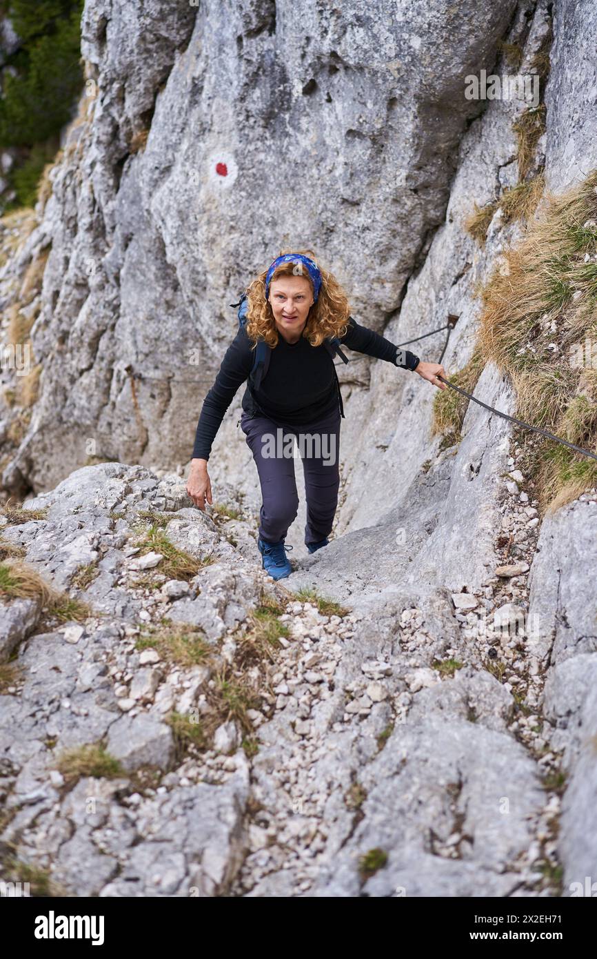 Alpinista che sale su una ripida parete sulla linea di sicurezza Foto Stock