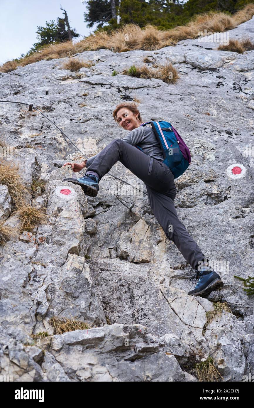 Alpinista che sale su una ripida parete sulla linea di sicurezza Foto Stock