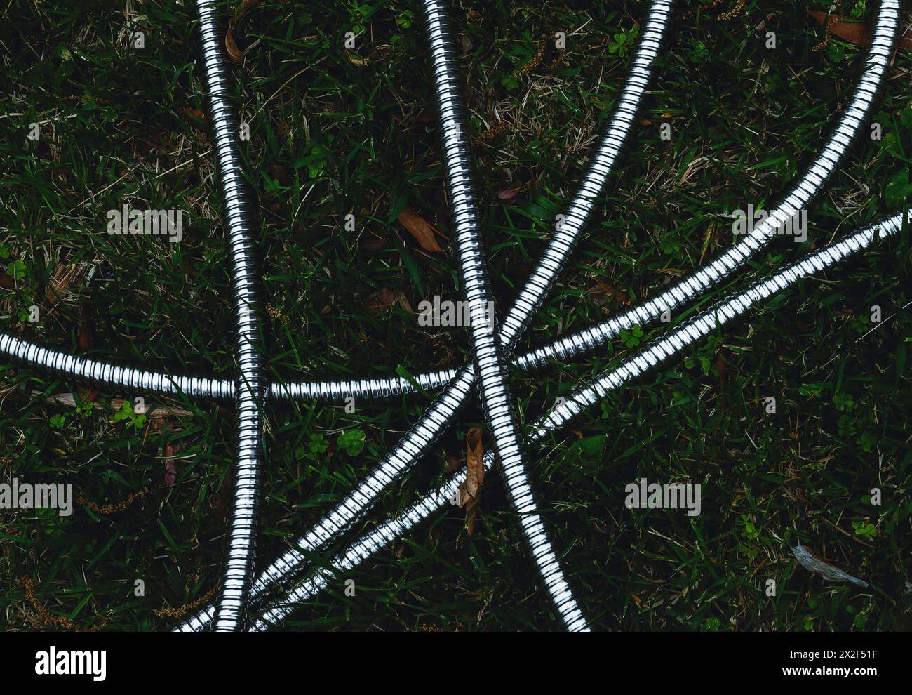 Un tubo da giardino in acciaio inox sull'erba Foto Stock
