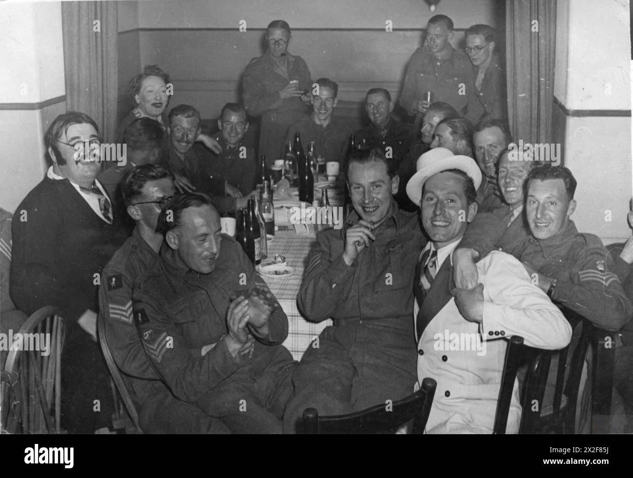 I membri dell'Army Film and Photography Unit, tra cui il sergente Eddy Smales, si siedono intorno a un tavolo in costume dopo aver eseguito una scenata durante una festa sergente in disordine alla caserma Kasr-el Nil, il Cairo, marzo 1943. Foto Stock I membri dell'Army Film and Photography Unit, tra cui il sergente Eddy Smales, si siedono intorno a un tavolo in costume dopo aver eseguito una scenata durante una festa sergente in disordine alla caserma Kasr-el Nil, il Cairo, marzo 1943. Foto Stock