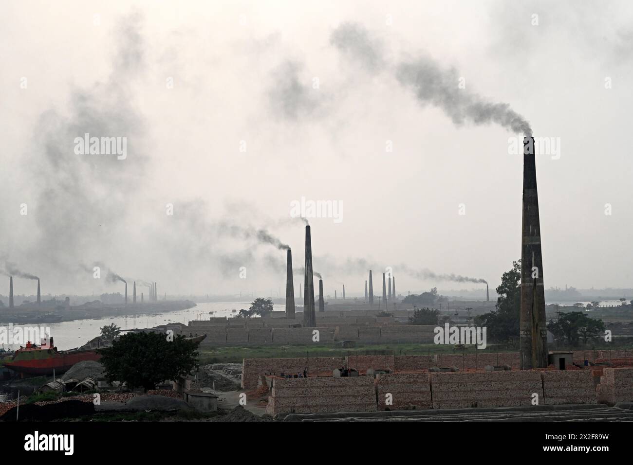 Dacca, Bangladesh. 22 aprile 2024. Il 22 aprile 2024 il fumo emana dai camini in una fabbrica di mattoni alla periferia di Dacca, Bangladesh. Le fabbriche di mattoni stanno causando un forte inquinamento atmosferico in Bangladesh. L'AQLI (Air Quality Life Index) classifica il Bangladesh come uno dei paesi più inquinati al mondo. Secondo l'Organizzazione Mondiale della Sanità (OMS), l'inquinamento atmosferico uccide circa sette milioni di persone in tutto il mondo ogni anno. Crediti: Mamunur Rashid/Alamy Live News Foto Stock
