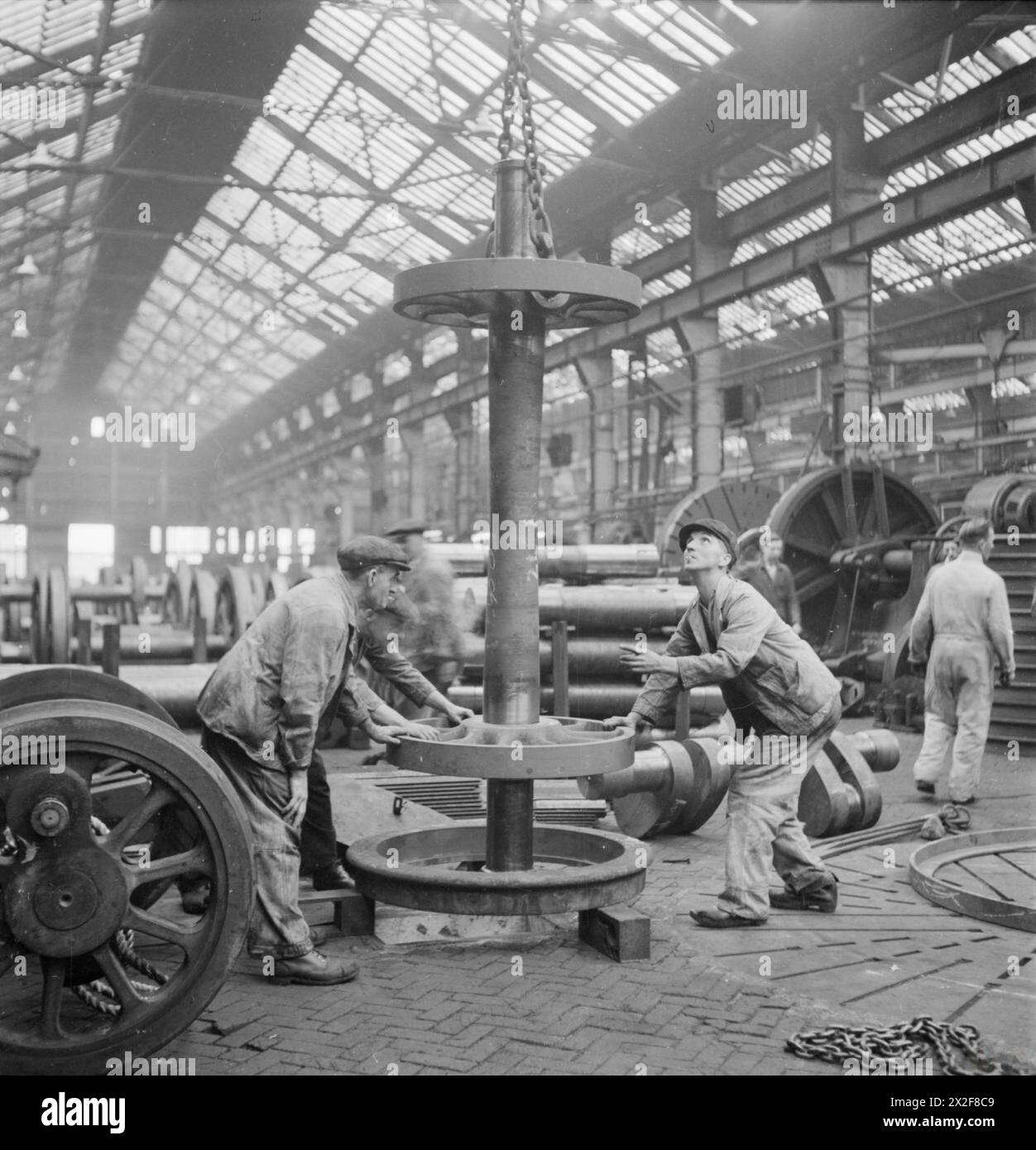 I lavoratori di un'officina di locomotive in Gran Bretagna montano i centri ruota in pneumatici caldi, utilizzando il restringimento mentre si raffreddano per fissare le ruote durante la produzione di locomotive ferroviarie nel 1945. Foto Stock