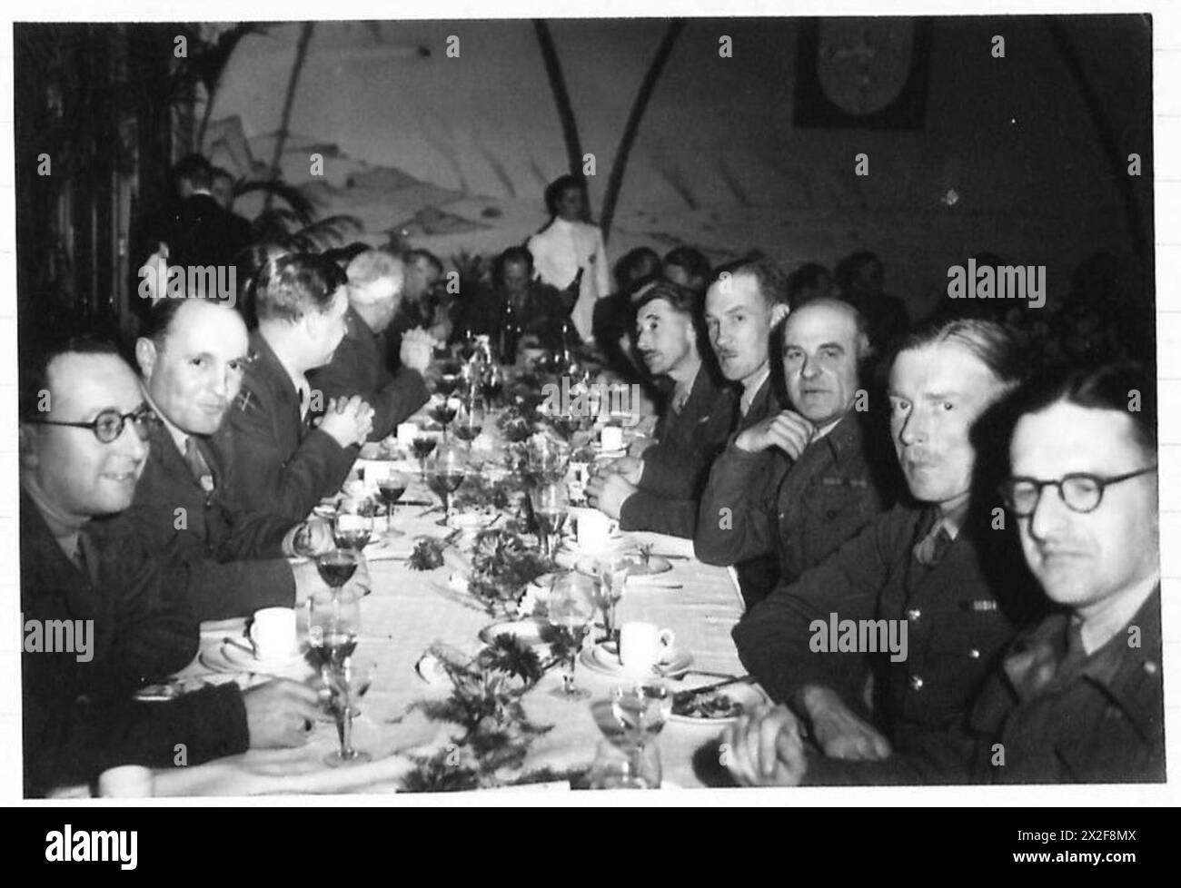 Ufficiali dell'esercito britannico, tra cui Leonard Mosley, Brig. C.L. Richardson, Maj-Gen. M.W.A.P. Graham e altri assistono ad una cena formale Alamein con posti a sedere annotati lungo il tavolo durante la seconda guerra mondiale, 21st Army Group. Foto Stock