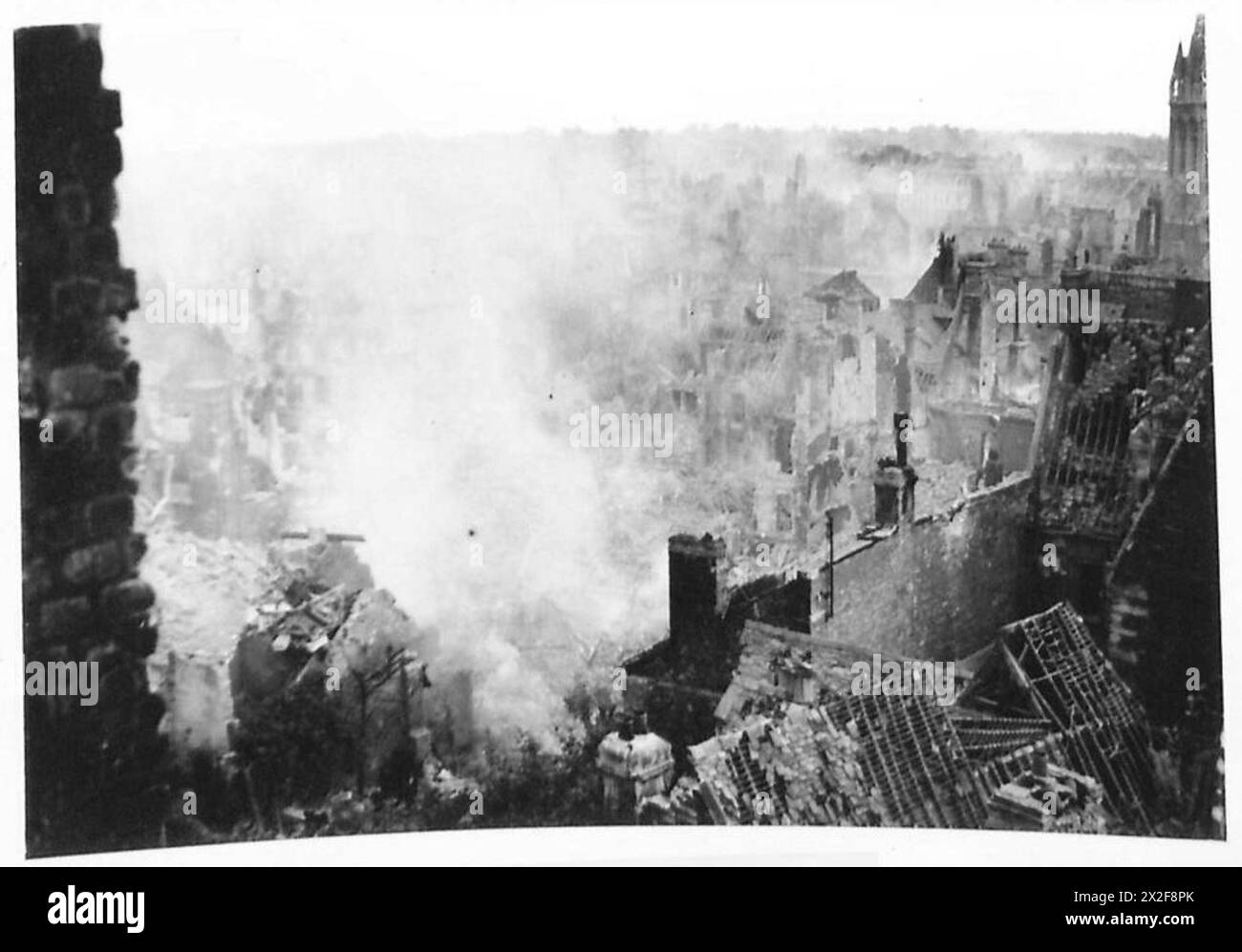 Le truppe britanniche entrano a Caen, passando attraverso le rovine brucianti della città dopo il combattimento, dimostrando la guerra urbana e le operazioni di occupazione durante la seconda guerra mondiale Foto Stock