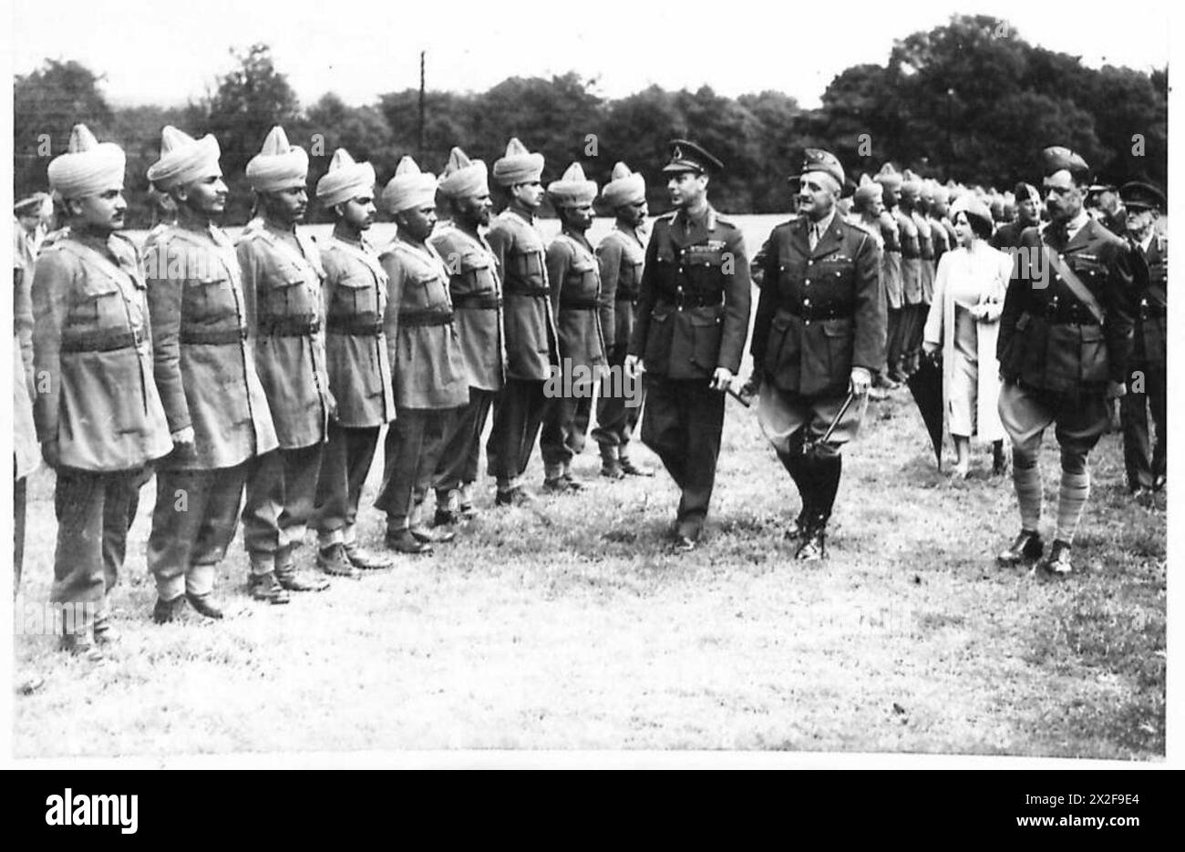 Il re e la regina ispezionano le truppe indiane camminando lungo i ranghi durante una visita cerimoniale dell'esercito britannico. Foto Stock