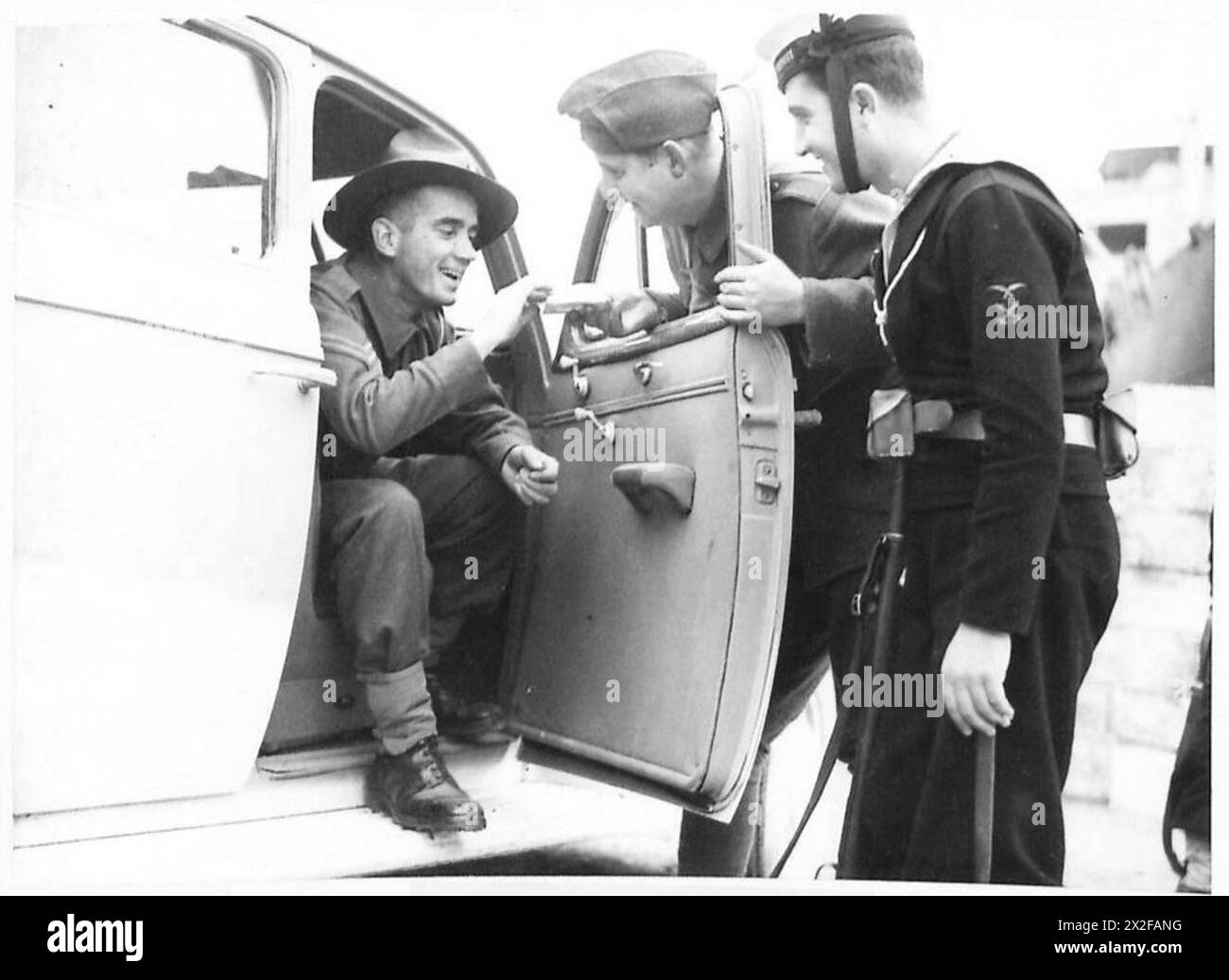 Un militare neozelandese con la British Air Force in Grecia riceve una sigaretta da un soldato e marinaio greco durante le interazioni. Foto Stock